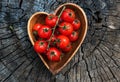 Cherry tomatoes in heart shape plate on old wooden surface, space for text. Royalty Free Stock Photo