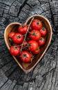 Cherry tomatoes in heart shape plate on old wooden surface, space for text. Royalty Free Stock Photo