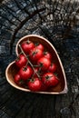 Cherry tomatoes in heart shape plate on old wooden surface, space for text Royalty Free Stock Photo