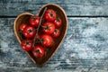 Cherry tomatoes in heart shape plate on old wooden surface, space for text Royalty Free Stock Photo