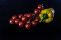 Cherry tomatoes and jellow sweet pepper on black background Royalty Free Stock Photo