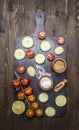 Cherry tomatoes, lime, spices, cucumber, laid out on a chopping board wooden rustic background top view close up Royalty Free Stock Photo