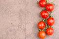 Red cherry tomatoes on a brown textured background, empty copy space