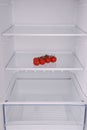 Cherry tomatoes in open empty refrigerator.