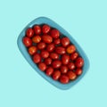 Cherry tomatoes in a plate, isolated on blue color background. Top view.