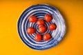 Cherry tomatoes plate on yellow wooden table. Top view