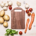 Cherry tomatoes, potatoes, carrots, parsley and mushrooms laid out around a cutting board place text,frame on wooden rustic ba Royalty Free Stock Photo