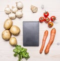 Cherry tomatoes, potatoes, carrots, parsley and mushrooms laid out around a notebook place text,frame on wooden rustic backgro Royalty Free Stock Photo