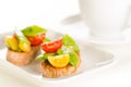 Cherry tomatoes and snow peas crostini with tea on white saucer Royalty Free Stock Photo