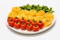 Cherry tomatoes, spaghetti and fresh basil on a platter on a white background