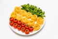Cherry tomatoes, spaghetti and fresh basil on a platter on a white background