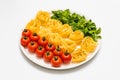 Cherry tomatoes, spaghetti and fresh basil on a platter on a white background