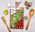 Cherry tomatoes, spinach leaves, mushrooms, laid out on a chopping board, beside devices are condiments and salad on wooden rustic