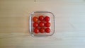 Cherry tomatoes in a square glass plate on a wooden background Royalty Free Stock Photo