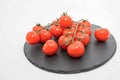 Cherry tomatoes on vine rest on black slate board isolated on white background Royalty Free Stock Photo