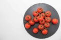 Cherry tomatoes on vine rest on black slate board isolated on white background Royalty Free Stock Photo