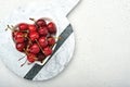 Cherry with water drops on heart shaped plate on white stone table. Fresh ripe cherries. Sweet red cherries. Top view. Rustic styl Royalty Free Stock Photo