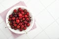 Cherry with water drops on heart shaped plate on white stone table. Fresh ripe cherries. Sweet red cherries. Top view. Rustic Royalty Free Stock Photo