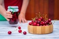 Cherry in wooden bowl and woman holding jar of preserved cherries fruit. Royalty Free Stock Photo