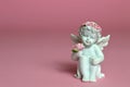 Cherub figurine on pink background