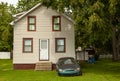 An old and rusty car parked in front of a single family home Royalty Free Stock Photo