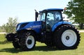 Large blue agricultural tractor on farm equipent dealership on a sunny summer day