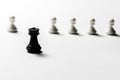 Chess black rook stands against white pawns. Symbol of leadership and confrontation. Horizontal frame