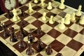 Chess board with black figures in focus and clock in black background. Royalty Free Stock Photo