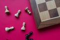 A chess board and black and white pawns over a bright pinkish background Royalty Free Stock Photo