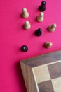A chess board and black and white pawns over a bright pinkish background Royalty Free Stock Photo