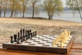 Chess board with chess pieces on bench with river embankment background. Chess game