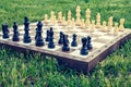 Chess board with chess pieces on green grass Royalty Free Stock Photo