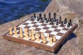 Chess board with chess pieces on rock with river embankment back Royalty Free Stock Photo