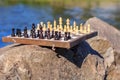 Chess board with chess pieces on rock with river embankment back Royalty Free Stock Photo