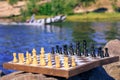 Chess board with chess pieces on rock with river embankment back Royalty Free Stock Photo