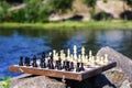 Chess board with chess pieces on rock with river embankment back Royalty Free Stock Photo