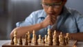 Chess board on table in front of school boy thinking of next move, tournament