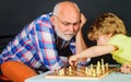 Chess competition. Grandpa and grandson playing chess spending free time together. Brain development and logic concept. Royalty Free Stock Photo