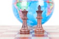 Chess figures in front of the globe Royalty Free Stock Photo