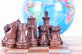 Chess figures in front of the globe Royalty Free Stock Photo