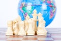 Chess figures in front of the globe Royalty Free Stock Photo