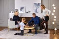 Chess game on coffee table, grandson is playing with his grandfather under supervision of his grandmother and mother. Royalty Free Stock Photo