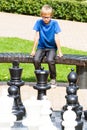 Chess game with giant chess piece. Boy playing strategic outdoor game on black and white board Royalty Free Stock Photo