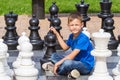 Chess game with giant chess piece. Boy siting and playing strategic outdoor game on black and white board Royalty Free Stock Photo