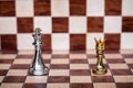 Chess game. Small pawn wearing golden crown stand confront the king. Business competitive and challenging
