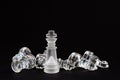 Chess of glass. The figure of the king standing over the defeated opponent`s pieces on a black background. Royalty Free Stock Photo