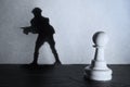 Chess pawn standing in a spotlight that make a shadow of soldier