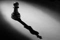 Chess pawn standing in a spotlight shadow of king Royalty Free Stock Photo