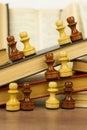 Chess pieces and books on a wooden table. Royalty Free Stock Photo