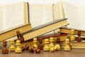 Chess pieces and books on a wooden table. Royalty Free Stock Photo